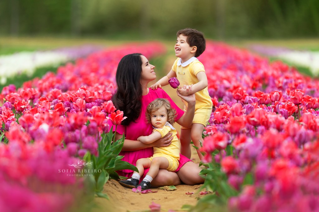 photo of mom and two babies in a field of tulips being photographed in new jersey