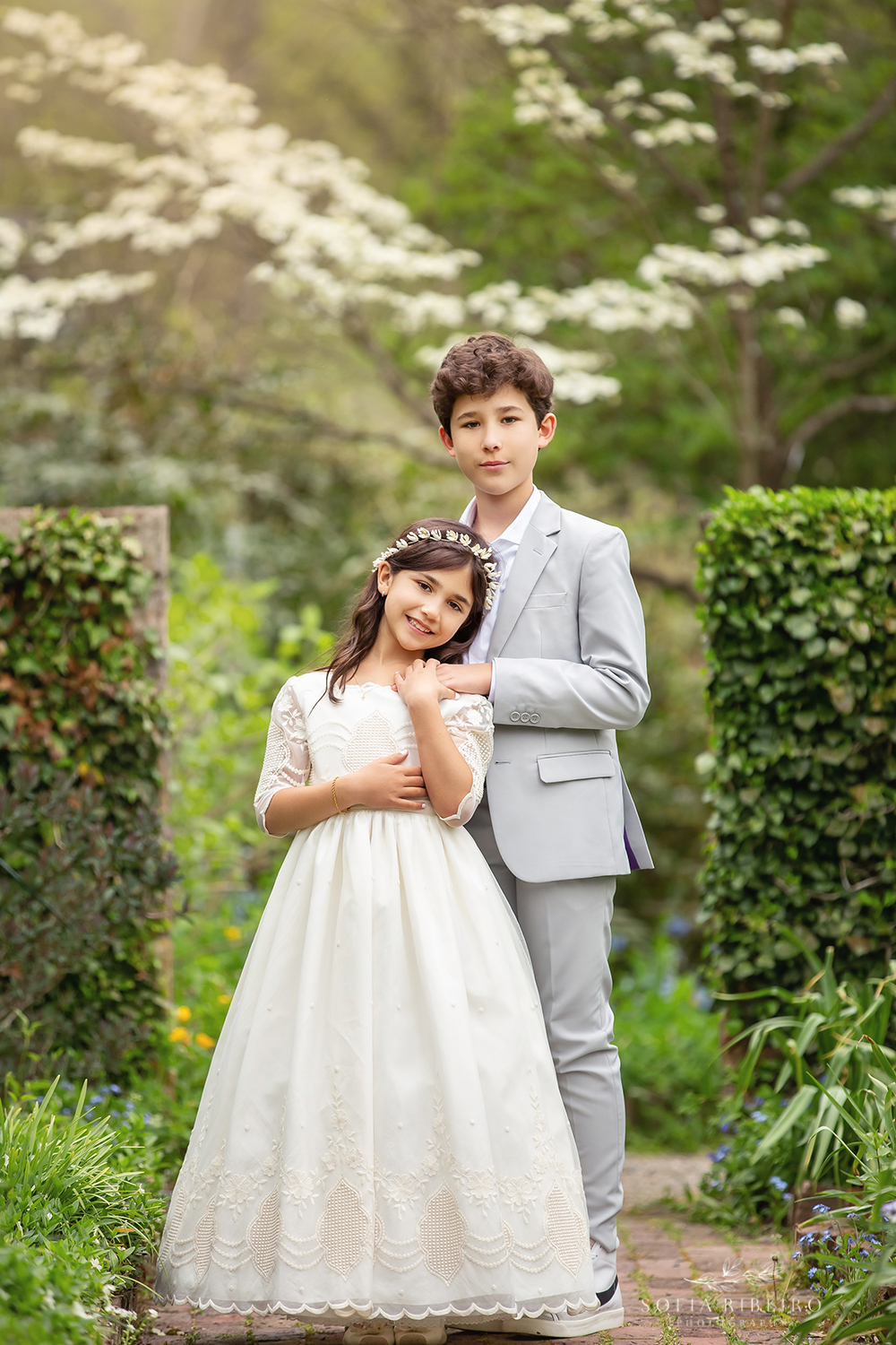 AN OLDER BROTHER POSES WITH HIS SISTER DURING HER COMMUNION
