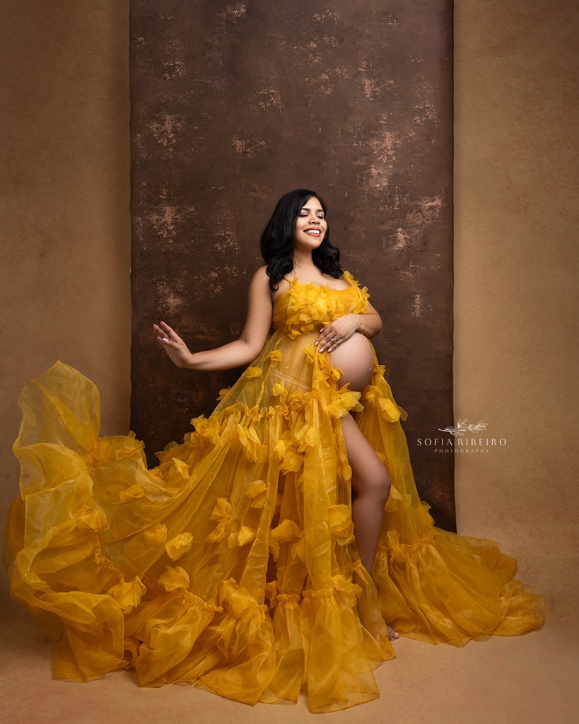 mom poses in a flowing gold dress for a maternity session in west new york nj