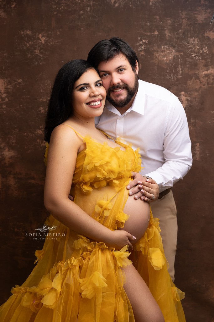 mom and dad pose together cradling the baby bump in a yellow dress during a maternity shoot in new york
