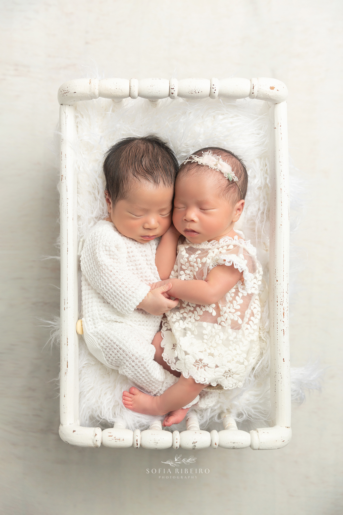 nj newborn photographer poses two twin siblings snuggled in a white crib prop