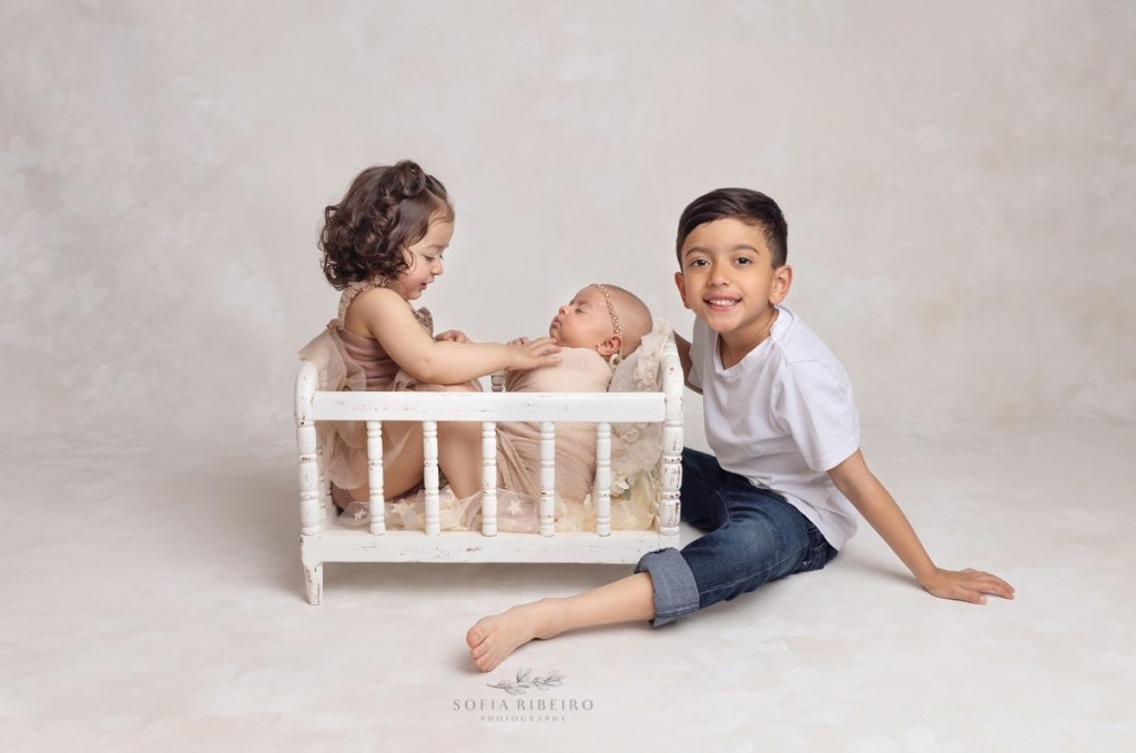 newborn with siblings in prop crib