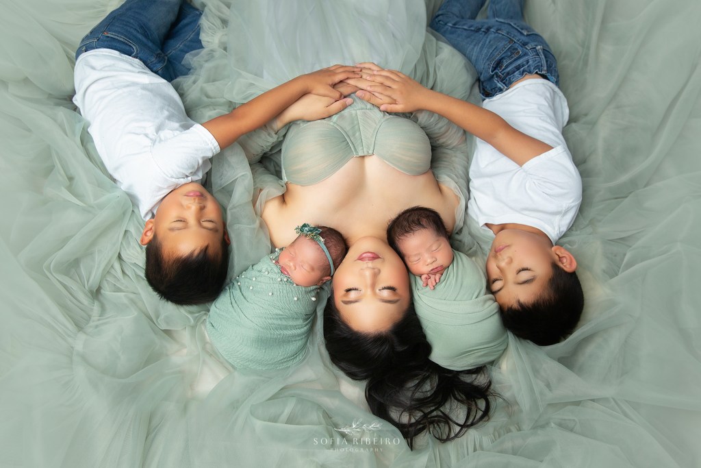 nj newborn photographer poses mom and all four of her babies on the floor during a portrait session
