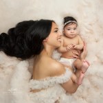 mom and baby girl pose together in tulle ruffles on the floor during a portrait session