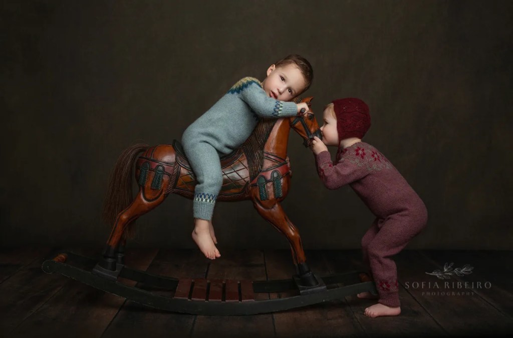 siblings play with a vintage rocking horse while taking photos in a new jersey photographers studio