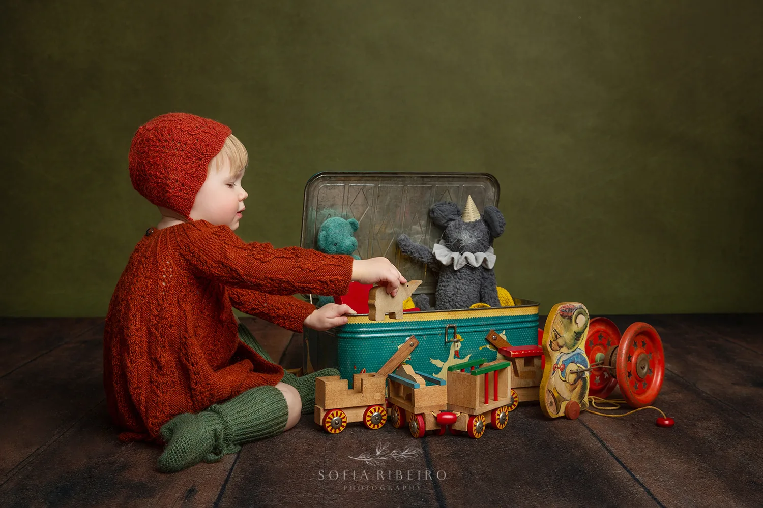 LITTLE GIRL IN HANDKNIT OUTFIT PLAYS WITH VINTAGE TOYS AFTER TAKING PHOTOS WITH NJ CHILDRENS PHOTOGRAPHER IN STUDIO
