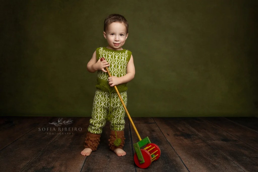 LITTLE BOY IN HANDKNIT OUTFIT PLAYS WITH VINTAGE TOYS AFTER TAKING PHOTOS WITH NJ CHILDRENS PHOTOGRAPHER IN STUDIO