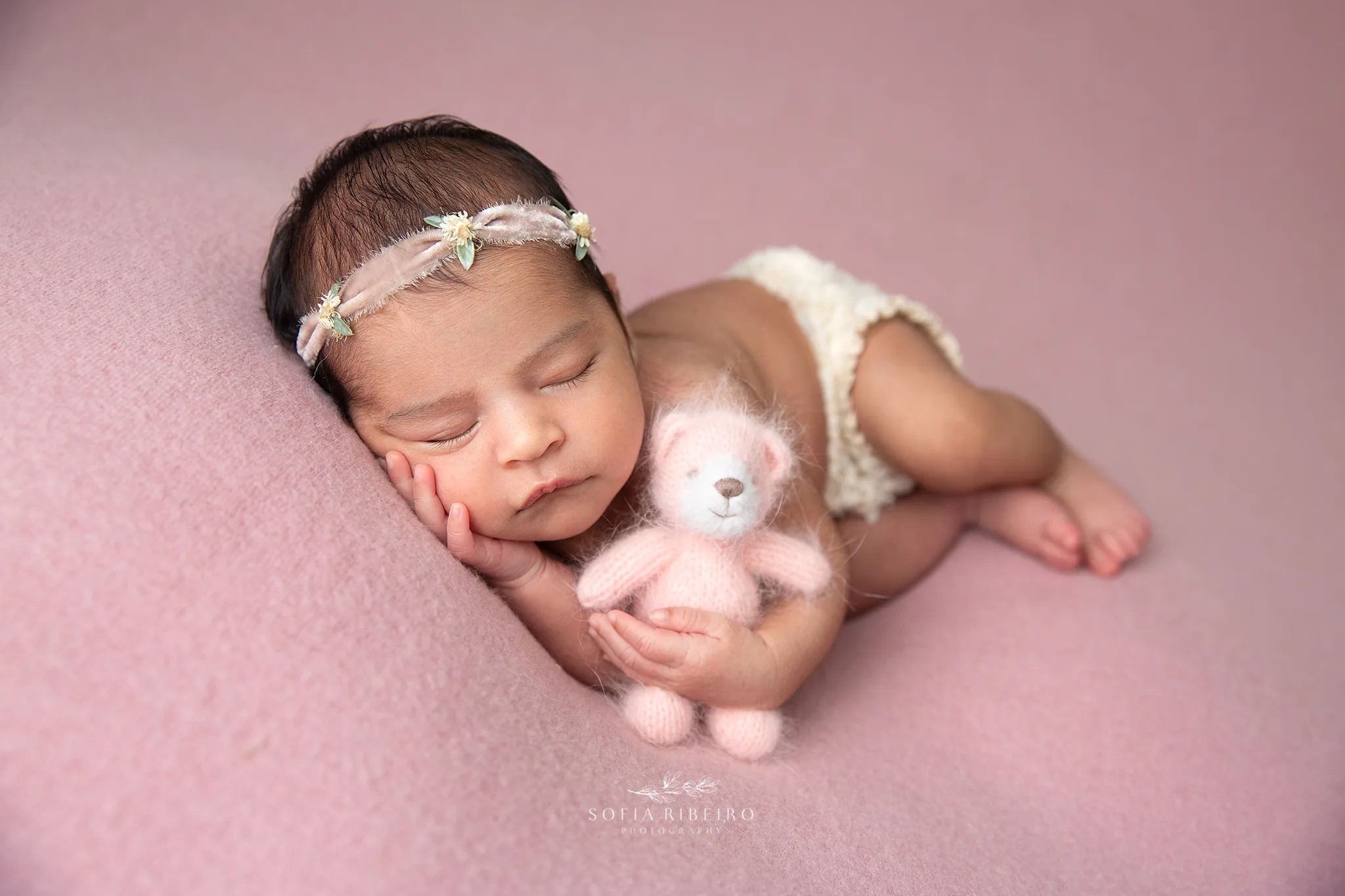 nj newborn photographer poses a baby girl on pink fabric with a pink stuffed bear