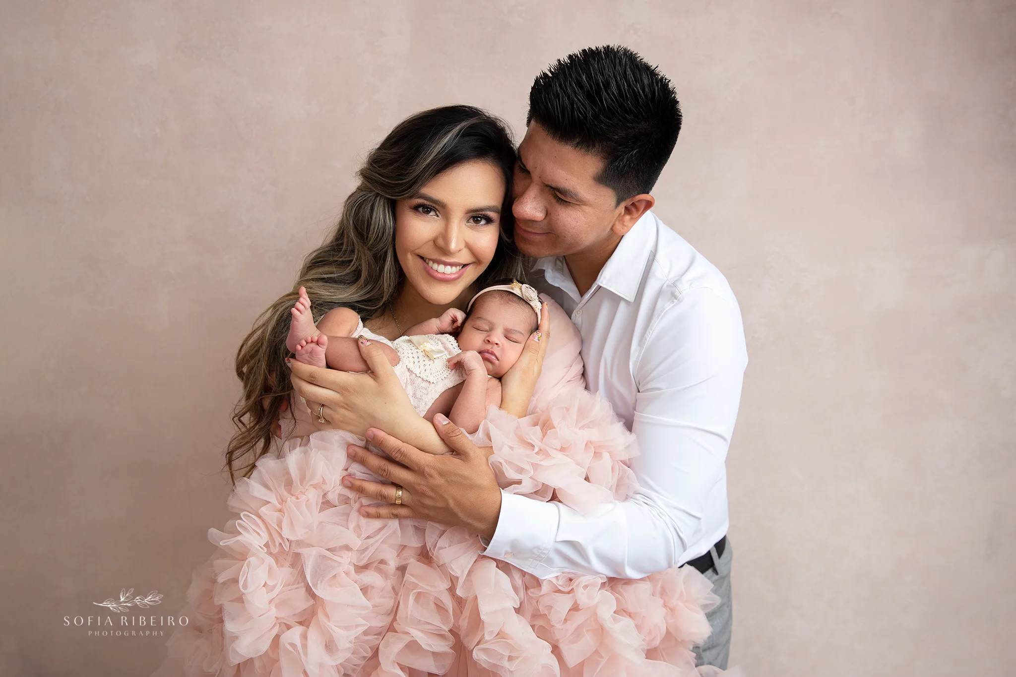 two parents lovingly look at each other while mom holds her newborn baby girl in a posed portraits by nj newborn photographer sofia ribeiro