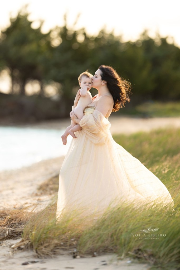 jersey shore family photographer, mom kissing baby in gown in the beach grasses