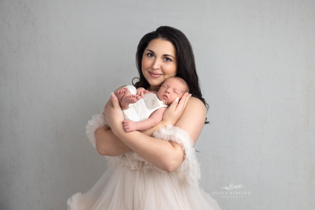 mom cradles her baby lovingly while dressed in neutral tons, during a session with a nj newborn photographer