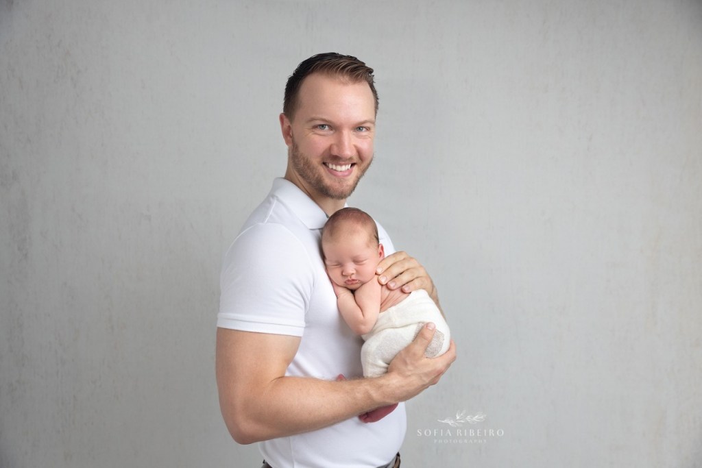 dad poses with his baby boy, smiling at the camera for photos