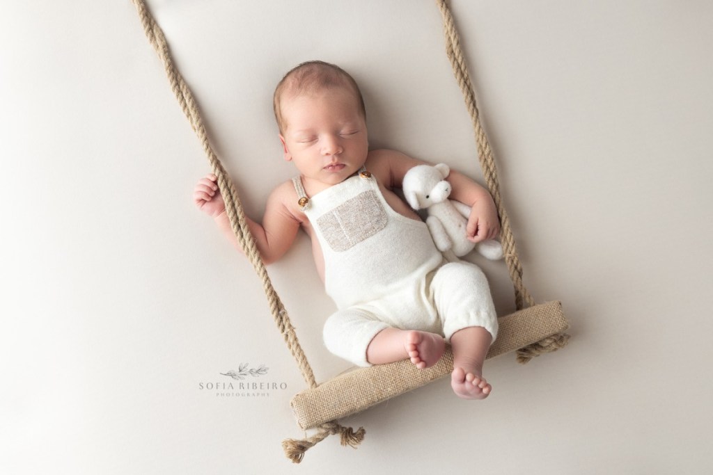 baby is posed on a fake swing prop with a bear during his photo session in new jersey