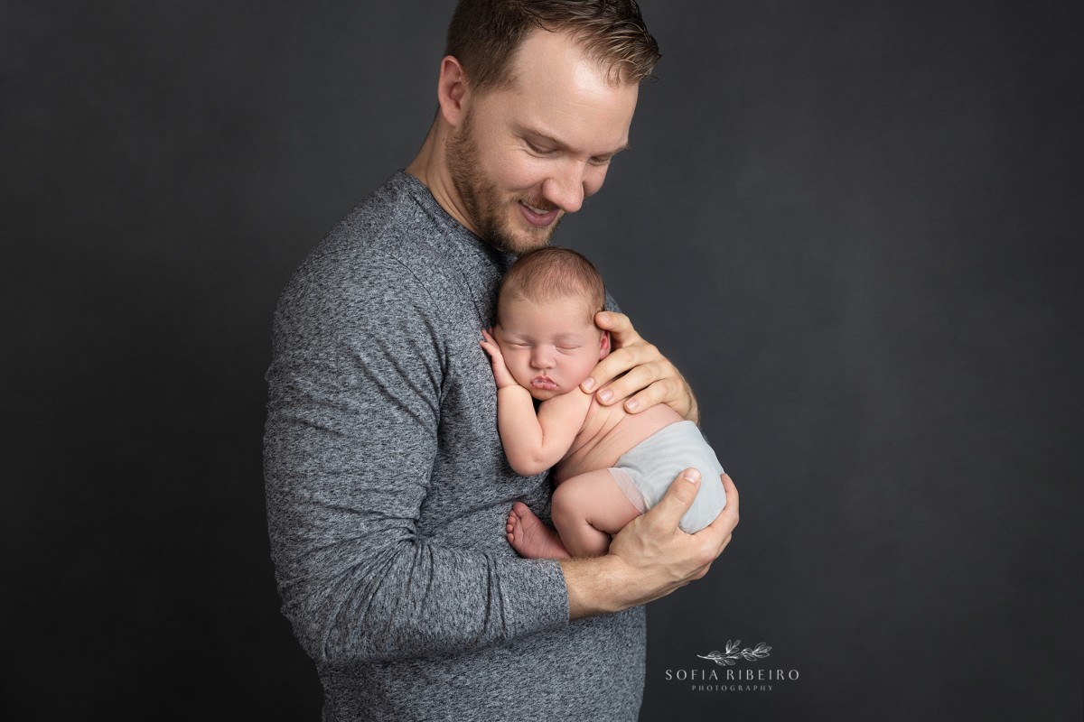 nj newborn photographer sofia ribeiro specializes in newborn portraits with family, like this shot of dad snuggling his baby boy