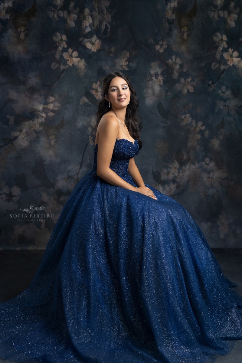 teen takes a formal seated portrait in navy blue gown at a nj childrens photography studio