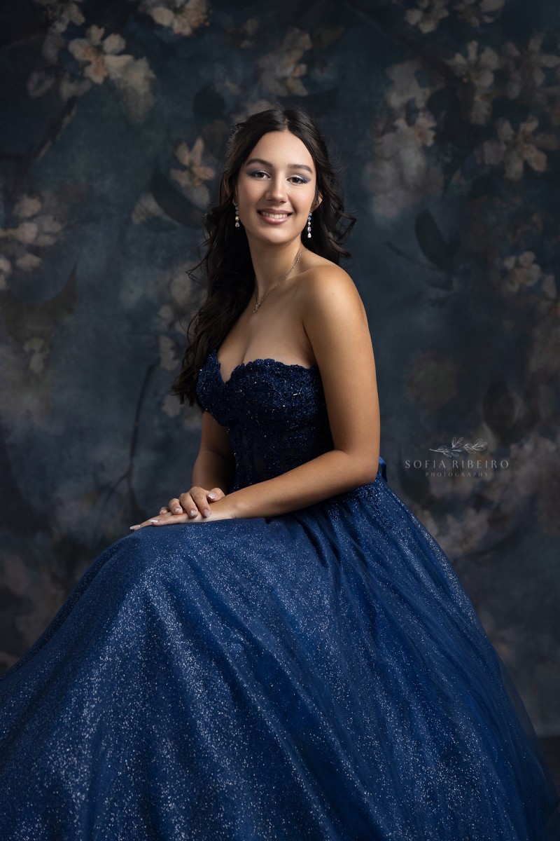 teen takes a formal seated portrait in navy blue gown at a nj childrens photography studio