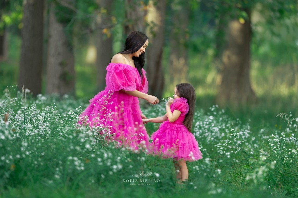 mom & me outdoor photoshot, mom and daughter in pink dresses, smelling flowers in a field