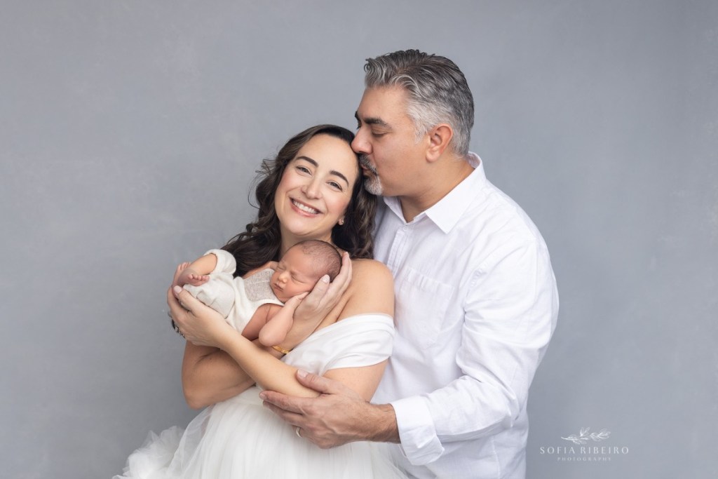 grey newborn session, baby in moms arms with dad kissing mom