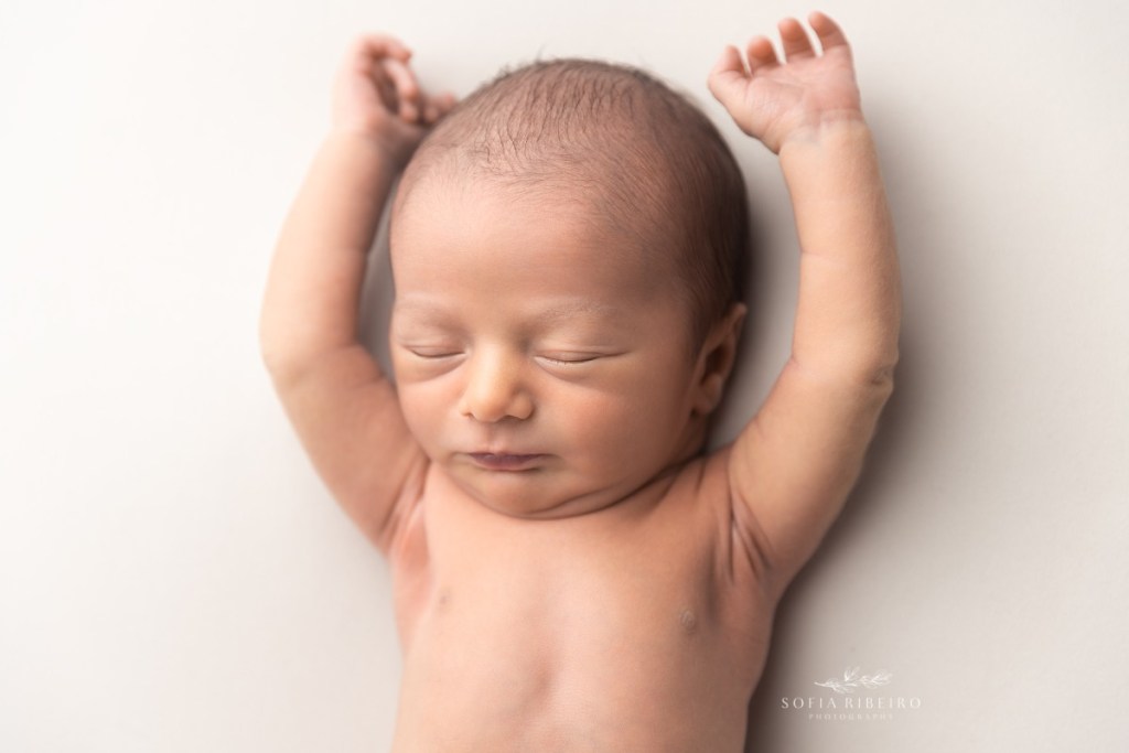 neutral beige baby newborn session with baby with arms over head