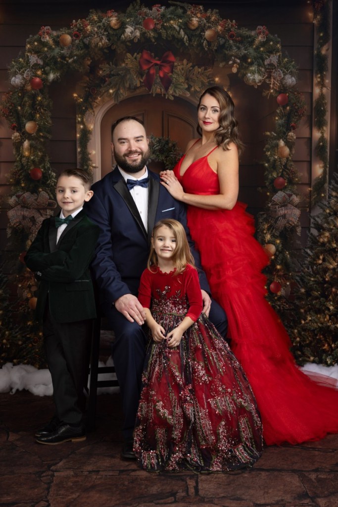 a family takes a formal holiday portrait with a holiday lights backdrop before doing christmas events for kids in nj