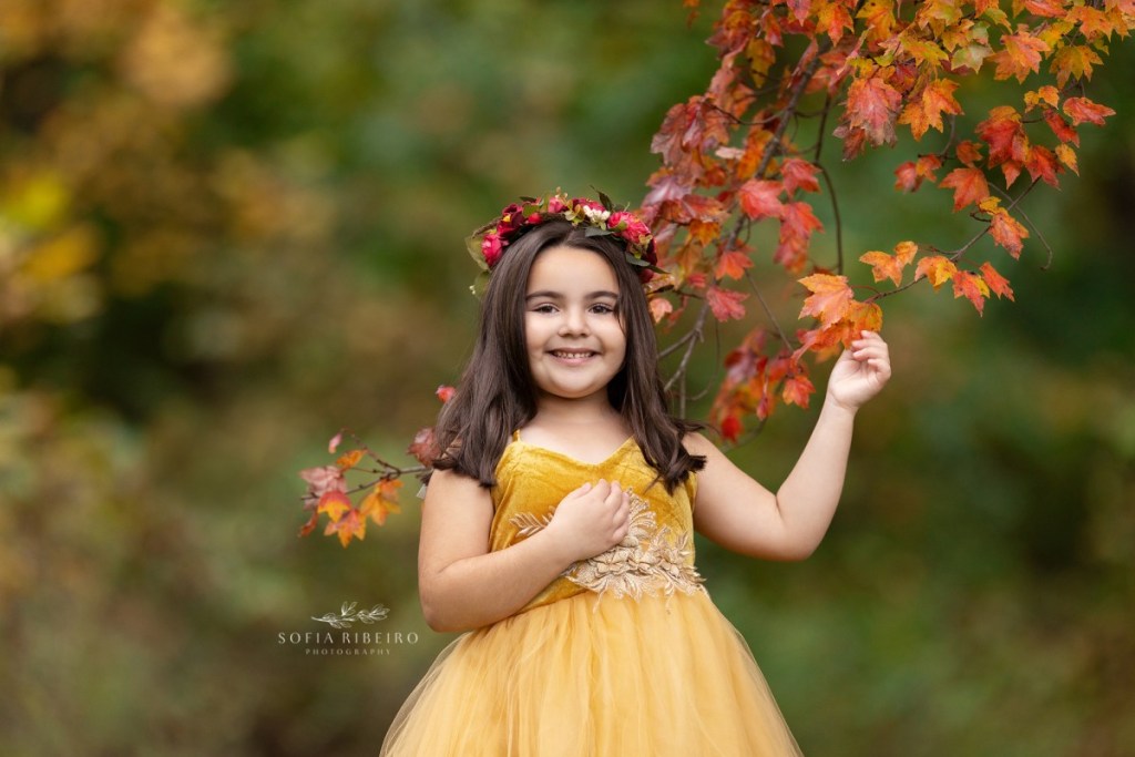 little girl poses with leaves in a gold dress during a childrens photo session in nj