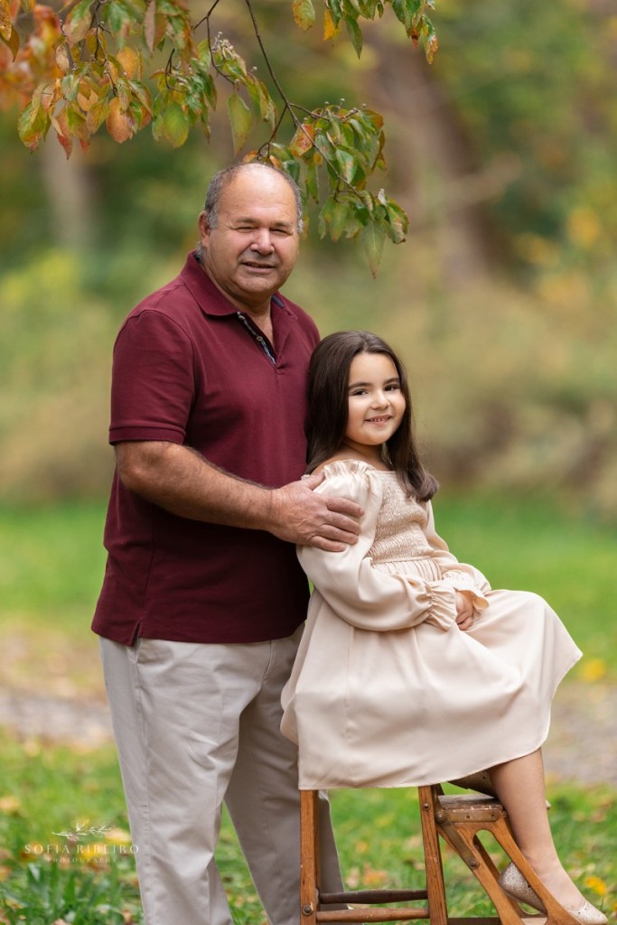 grandfather poses with granddaughter during a family session