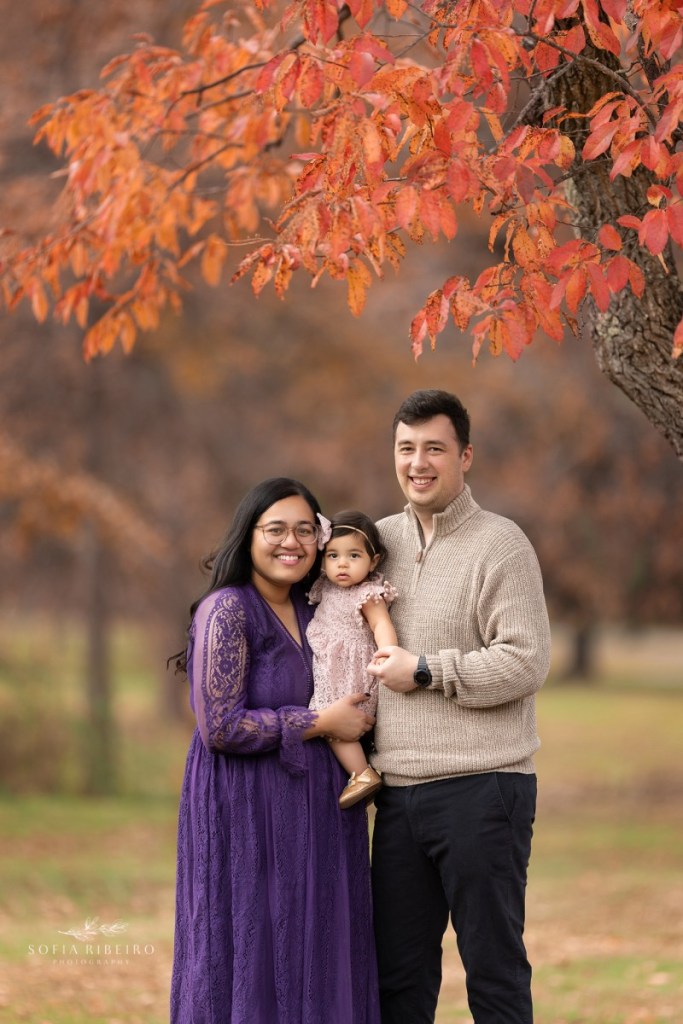 mom dad and baby smile together before taking photos during a fall family session in nj