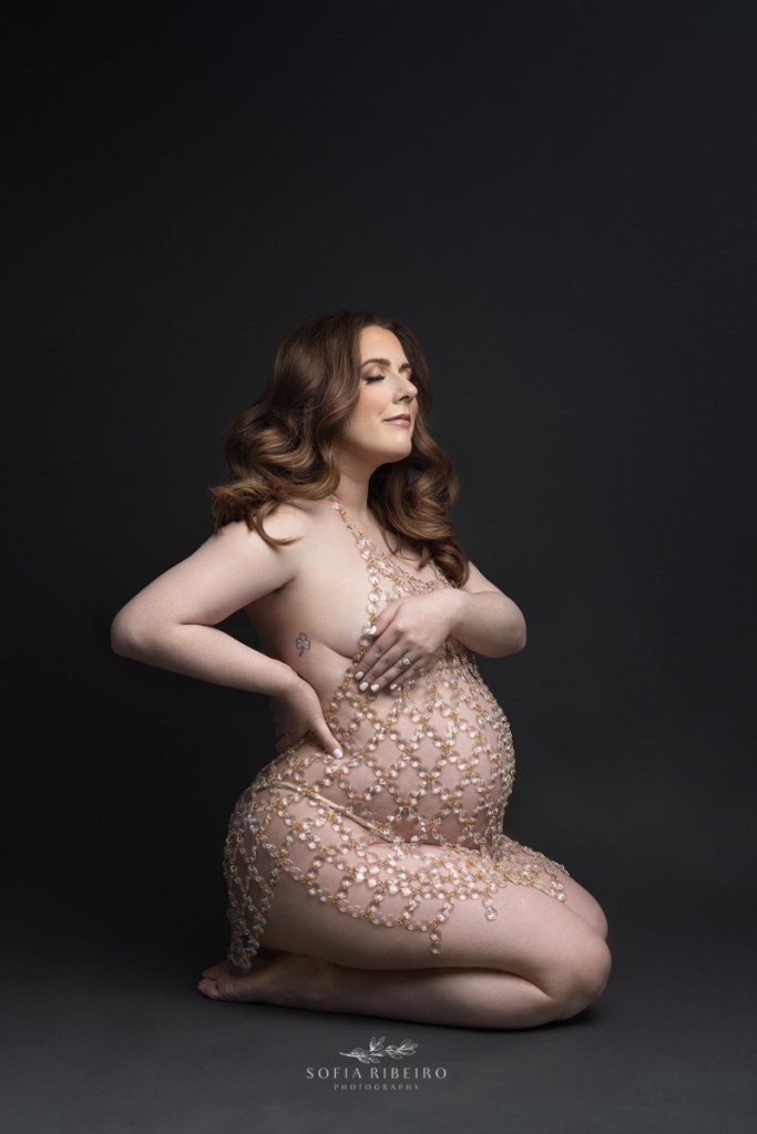 pregnant mom poses in a crystal dress against a dark background during a maternity session in nj