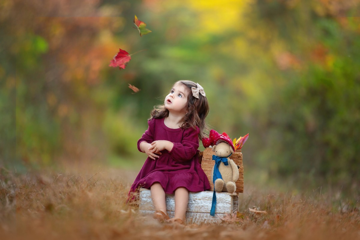 baby girl plays in the leaves outdoors in fall before heading to an nj mommy and me class