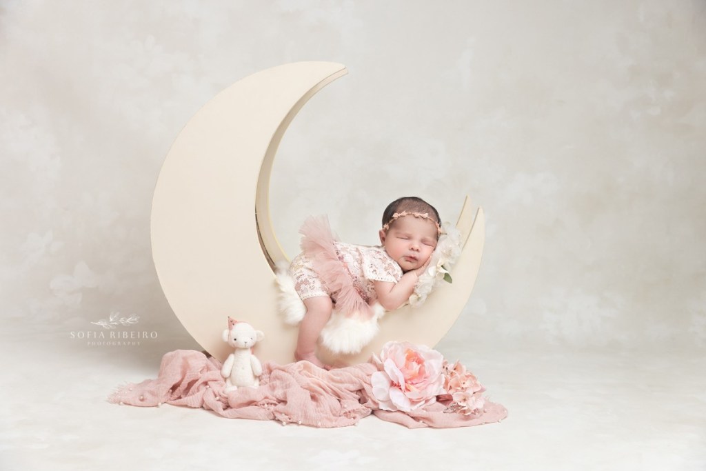 baby girl smiles in her sleep on a moon prop before her newborn photo session