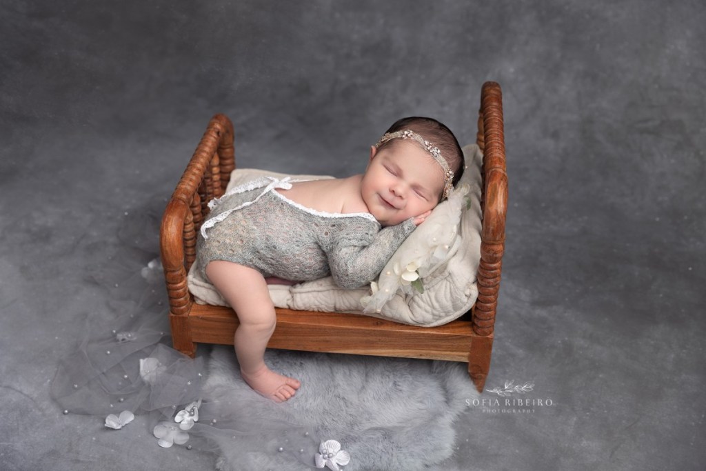 baby girl sleeps soundly in a miniature bed during a nj newborn photography session