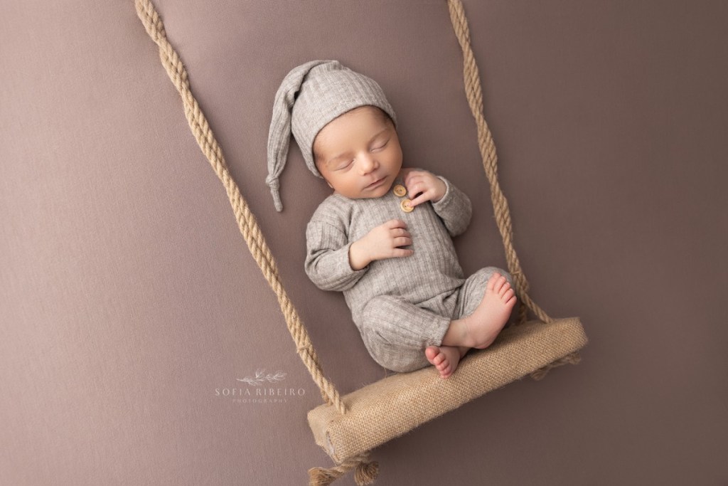 newborn baby is posed on a swing prop during a newborn session