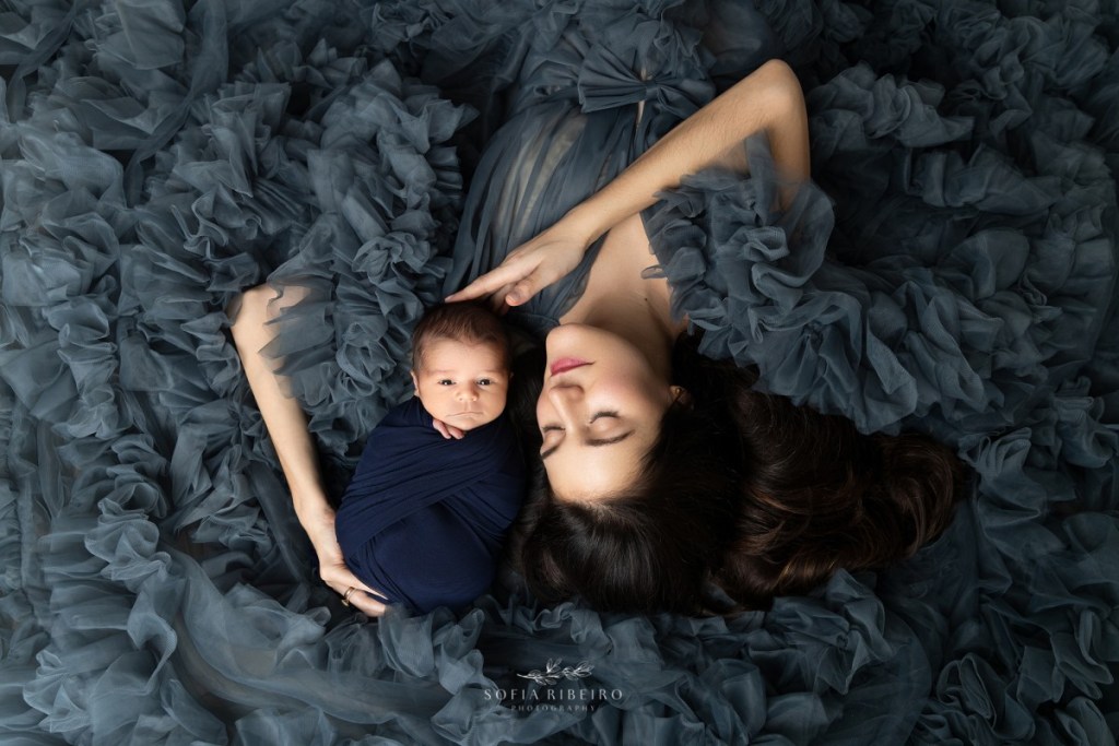 mom cradles baby while dressed in a blue gown