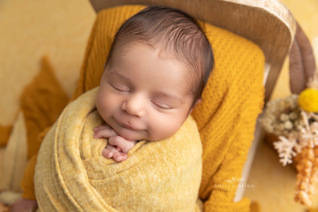 newborn boy wrapped in a mustard yellow fabric during a newborn session