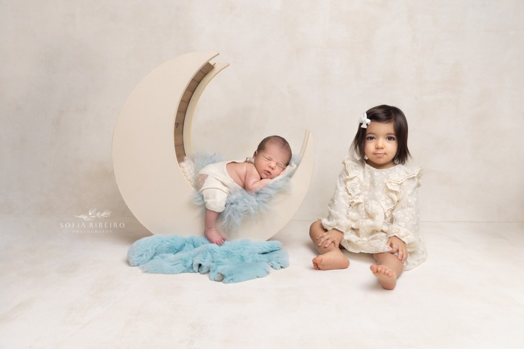 newborn baby boy posed in blue outfit on moon prop