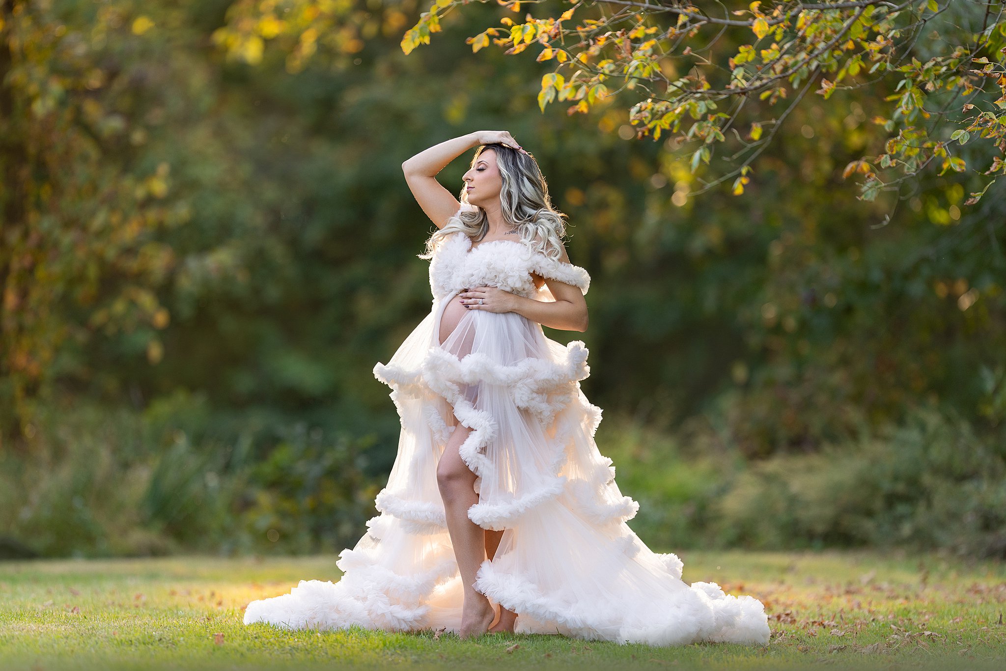 A mom to be walks through a forest field at sunset in a white tule maternity gown after her 3d ultrasound new jersey