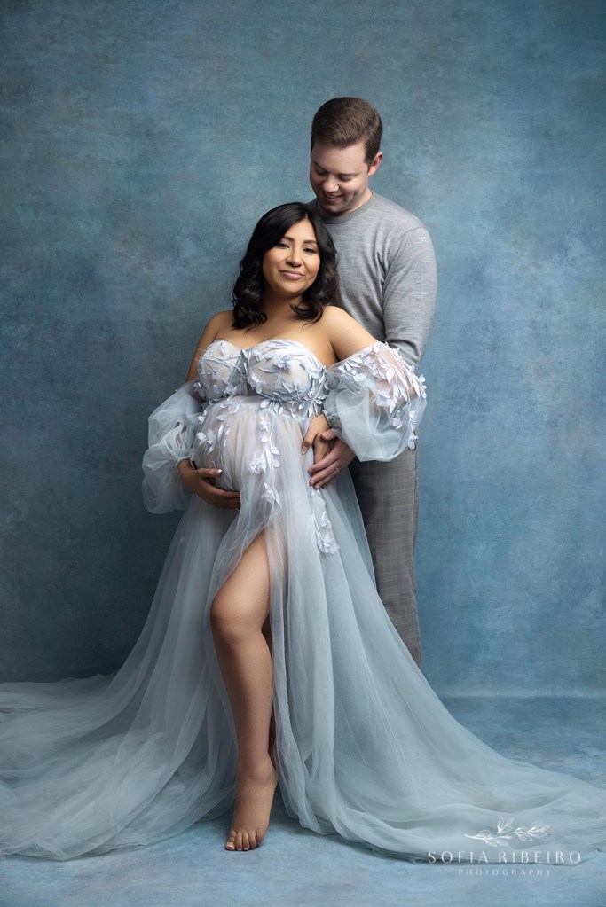 dad looks lovingly at mom during their maternity session in nj dressed in shades of blue
