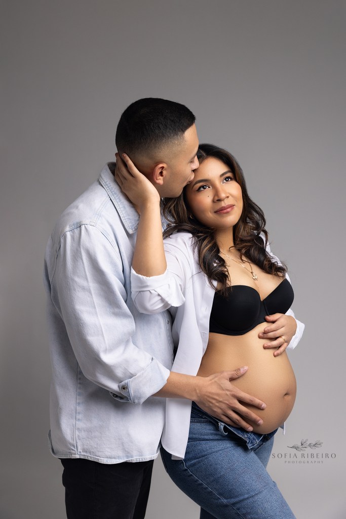 mom holds dad's face while he cradles her belly during a nj maternity photo session