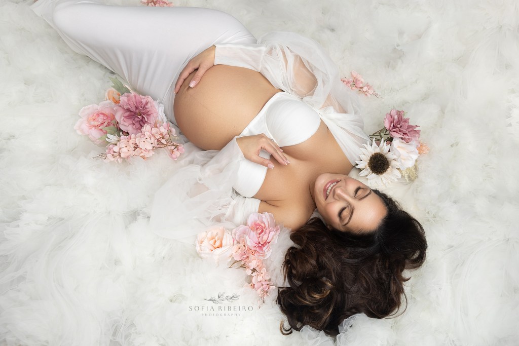 Mom lays in tulle and flowers while posing for a portrait during an NJ maternity session
