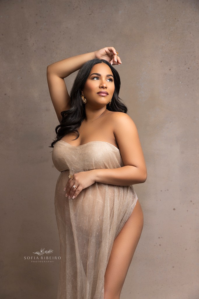 mom poses with an arm over her head and holding her belly during a maternity photo shoot in nj