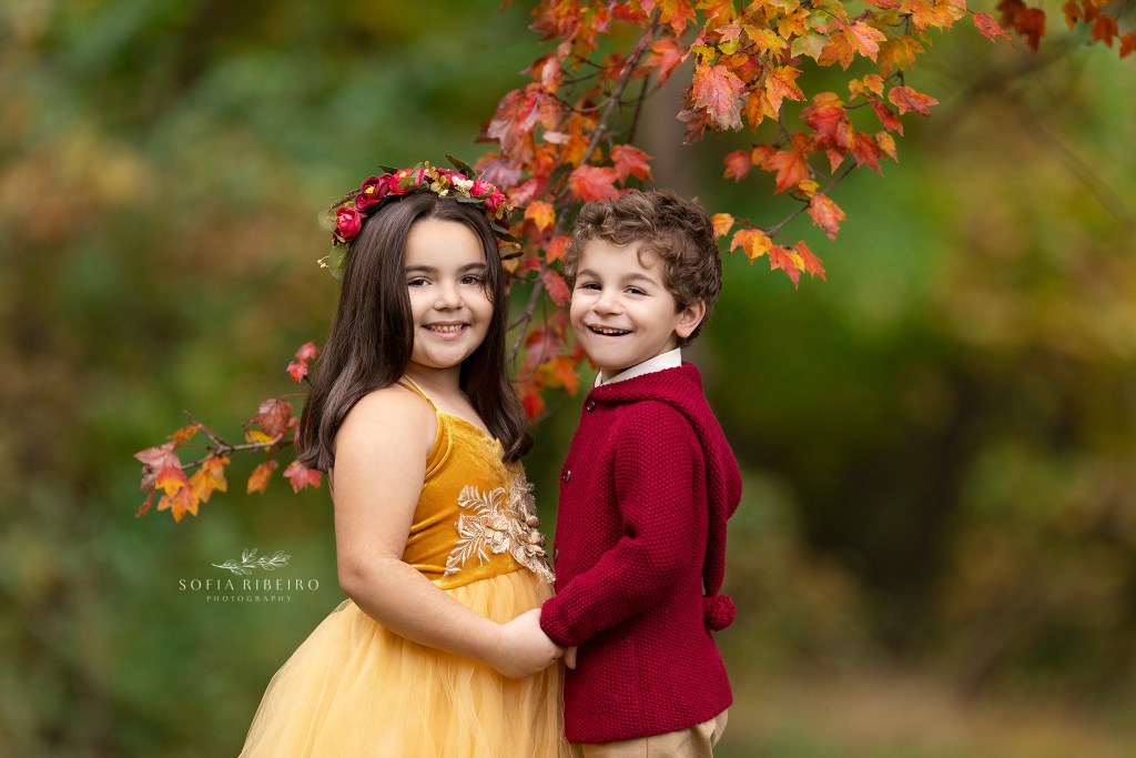 two siblings smile into the camera dressd in fall colors during an outdoor children's photo session in new jersey