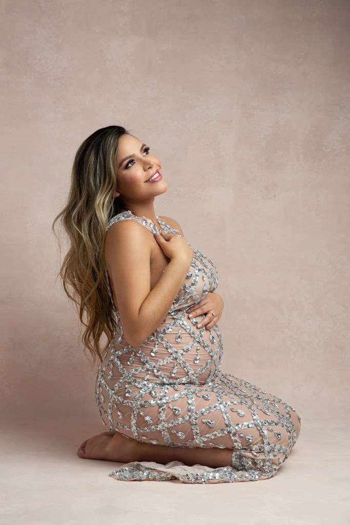 mom poses in gold and green with flowers during a maternity session with an nj photographer