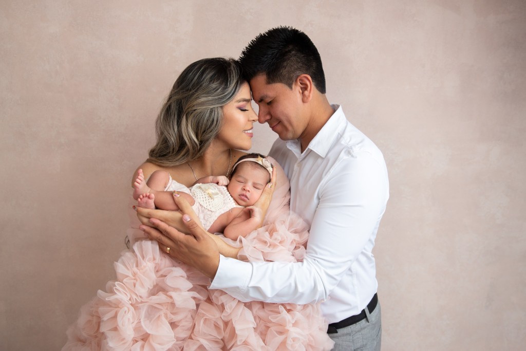 dad and mom snuggle lovingly while holding their new baby girl for photos during a nj newborn photo session