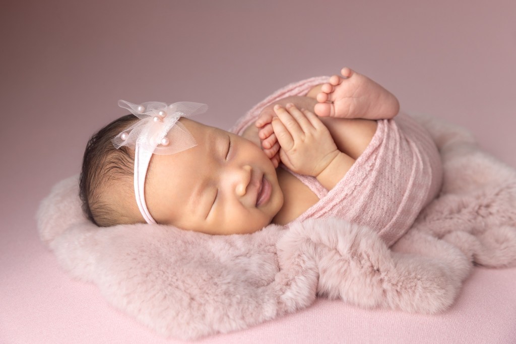 newborn girl with a pink bow and wrap during newborn photos