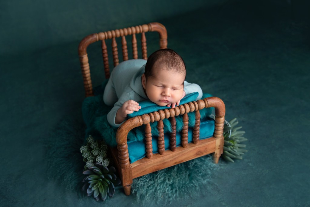 baby boy posed on a newborn prop while taking photos