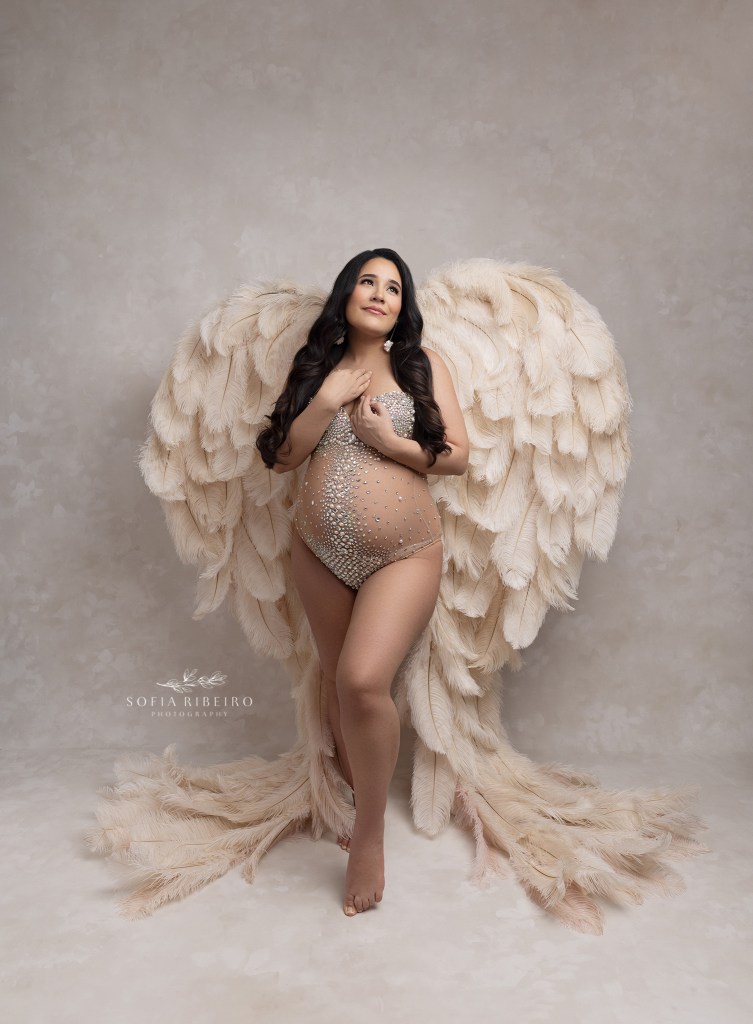 mom smiles and poses in angel wings and a rhinestone bodysuit during a maternity session in rahway nj