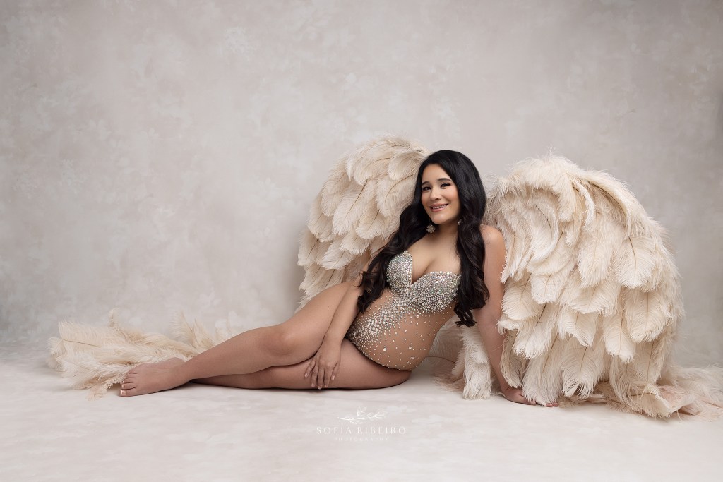 mom smiles and poses in angel wings and a rhinestone bodysuit during a maternity session in rahway nj
