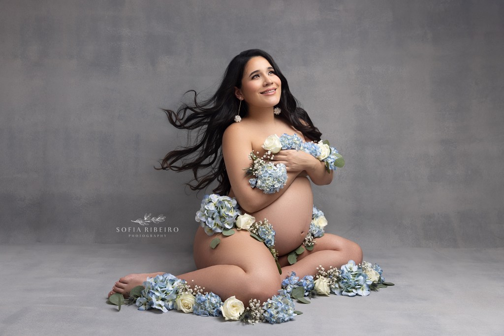 moms hair blows back during a maternity session as she's covered in flowers highlighting her bump in rahway nj