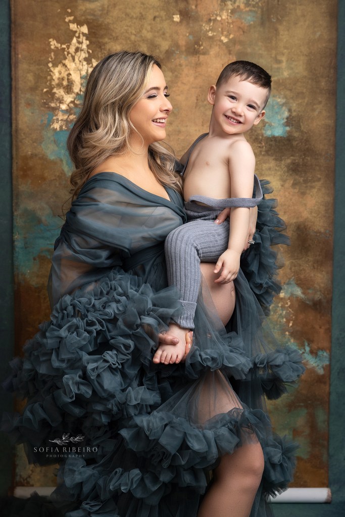 mom plays with her toddler son while smiling at the camera during a maternity session in clark nj