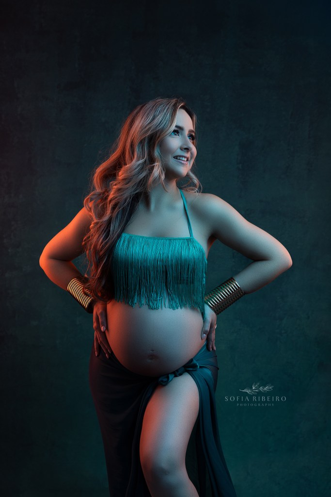 mom is illuminated in blue and orange gel lighting for a pregnancy photoshoot